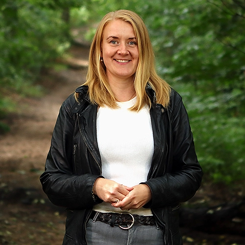 Portrait von Regina Schmitz, in einem Wald stehend